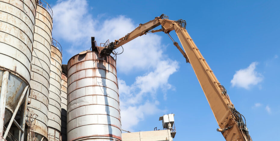 A crane is being used outside to dismantle an old tank