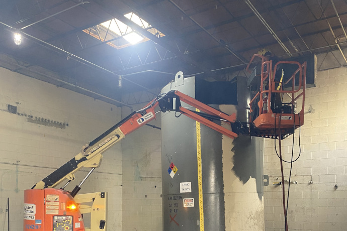 Vessel Inspector using a cherry picker to inspect an industrial tank.