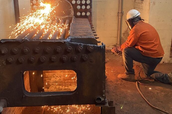 Remediation work in progress: worker cutting rusted metal with a torch, showcasing Archview Services' demolition and removal capabilities.