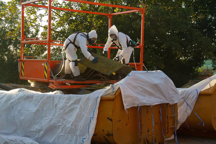 Workers in hazmat suits conduct site remediation.