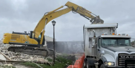 Demolition contractor tearing down building with excavator
