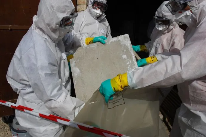Group of workers in hazmat suits removing asbestos from a commercial building