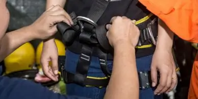 Construction working putting on a safety body harness during Fall Protection Training